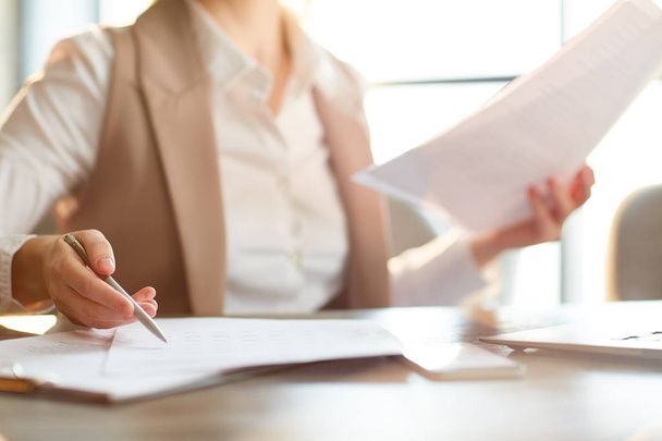 Femme d'affaires avec stylo pointant vers l'un des papiers sur la table lors de la lecture des contrats
 - Photo, image