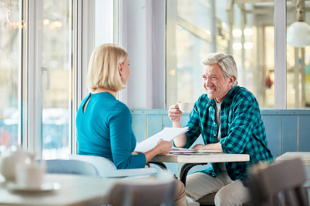 Ystävälliset ikäiset kollegat puhuvat kahvilassa teekupilla ja keskustelevat työhetkistä.
 - Valokuva, kuva