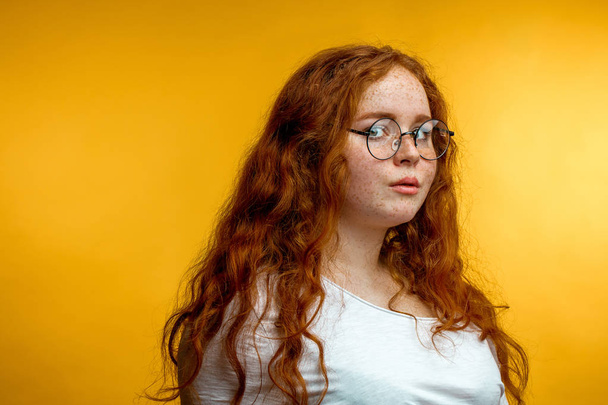 Молодая женщина с отстегнутыми рыжими волосами изолированы на желтый, с спокойным выражением лица
 - Фото, изображение