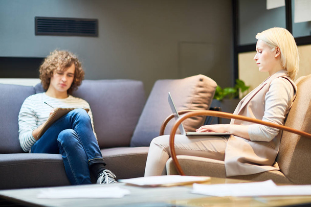 Hombre y mujer joven sentado en la oficina moderna, lluvia de ideas y hacer plan de trabajo de forma individual
 - Foto, Imagen