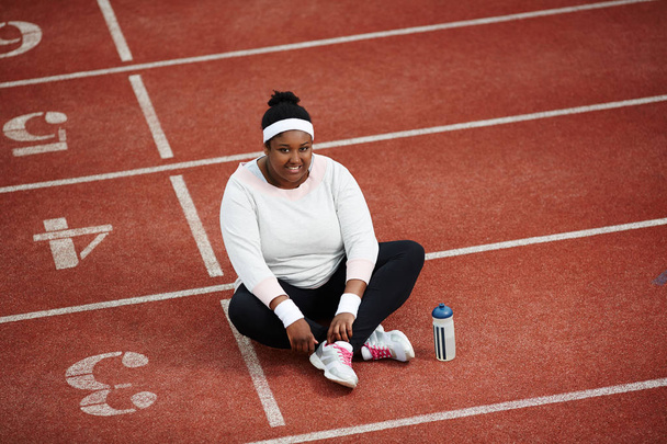 Cheerful and friendly female in sportswear having rest on race track - Foto, Bild