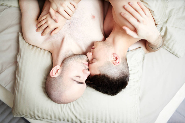 Overview of amorous guys lying on pillow while sleeping in embrace - Foto, Bild