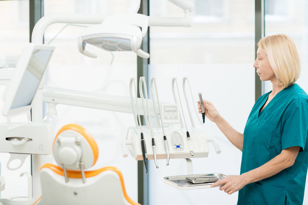 Zahnarzthelferin überprüft alle Instrumente und Bohrer, die für die orale Untersuchung und Heilung notwendig sind - Foto, Bild
