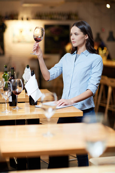 Mujer joven sosteniendo una copa de vino tinto en el restaurante
 - Foto, Imagen