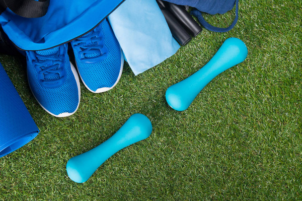 on a green lawn, a blue set of things for doing sports, a bag with things and shoes, and two dumbbells - Φωτογραφία, εικόνα