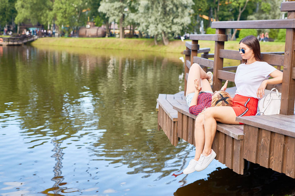 Dziewczyna w okularach słonecznych i casualwear słuchając jej przyjaciel opinia na temat parku są zwiedzanie i relaks w - Zdjęcie, obraz