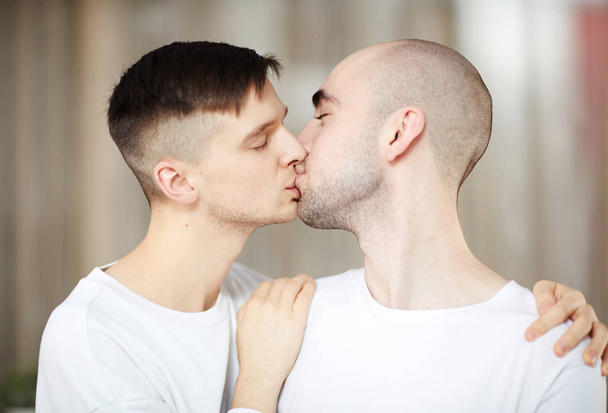 Twee jonge homo liefhebbers delen Goedemorgen kussen thuis - Foto, afbeelding