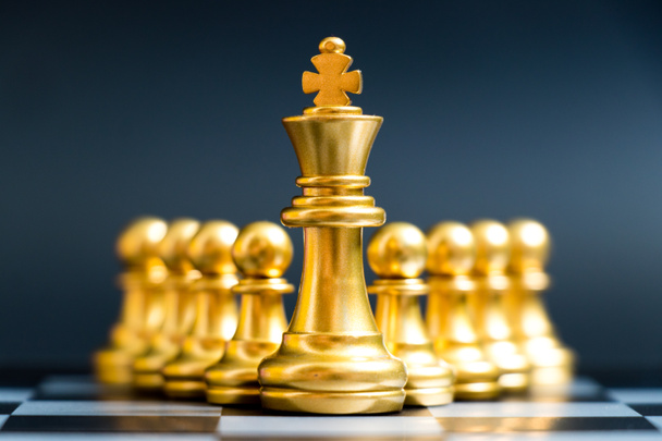 Zlatý král šachové figurky stojí před pěšcem na černém pozadí (Koncept vedení, management) - Fotografie, Obrázek