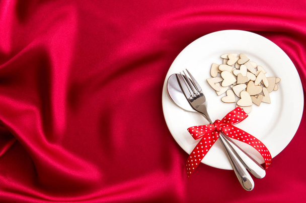  forme de coeur avec plaque blanche vide avec fourchette et cuillère sur tissu de soie rouge pour dîner d'amour concept
 - Photo, image