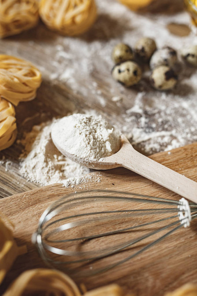 Raw homemade pasta and ingredients for pasta on a wooden background - Foto, afbeelding