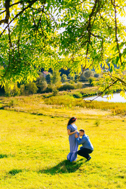 Bir adam karısının göbek Gölü yakınındaki bir yeşil çimenlerin üzerinde kisses - Fotoğraf, Görsel