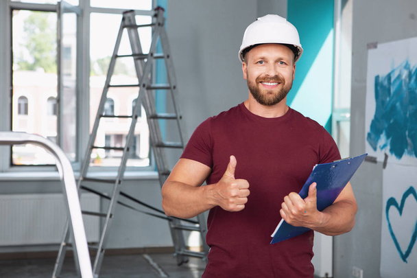 Cheerful builder showing a thumb up - Фото, изображение