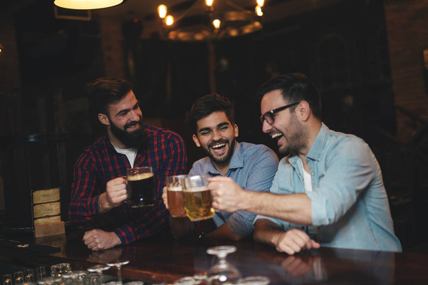 De jongens in de pub drinken bier en kijken naar de voetbalwedstrijd - Foto, afbeelding