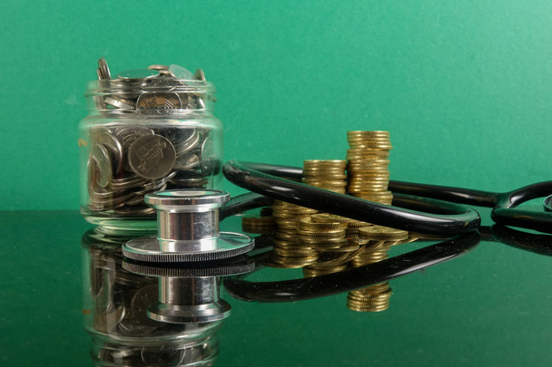 Medische kosten concept met de stethoscoop en munten .op een groene achtergrond. - Foto, afbeelding