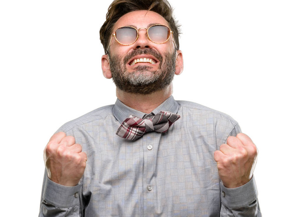 Middle age man, with beard and bow tie happy and excited celebrating victory expressing big success, power, energy and positive emotions. Celebrates new job joyful isolated over white background - Photo, Image