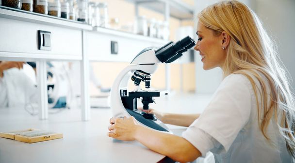 Young female scientist looking through microscope in laboratory - Foto, Imagem