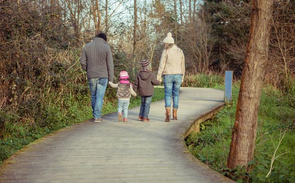 Счастливая семья, идущая вместе, держась за руки в лесу
 - Фото, изображение
