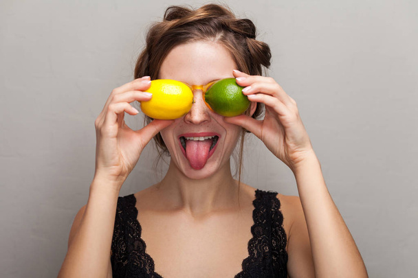 portrait of attractive woman in glasses holding lime and lemon in front of eyes  - Foto, immagini