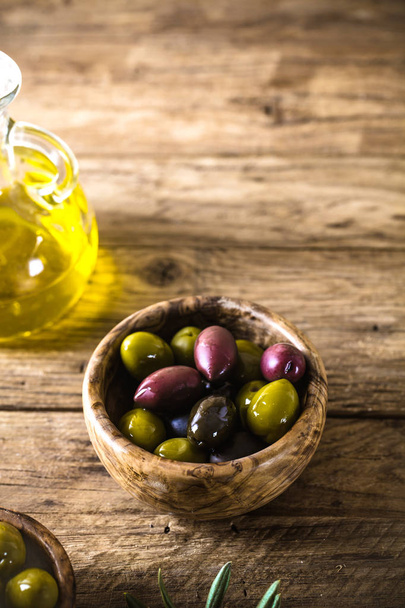 olives on olive branch. Wooden table with olives and olive oil - Foto, afbeelding