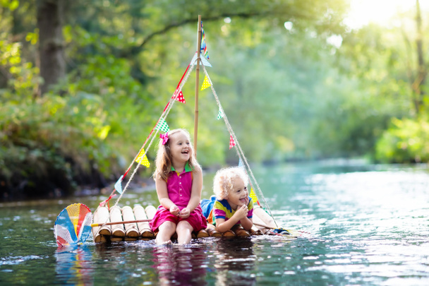 Zwei Kinder auf Holzfloß fangen Fische mit einem bunten Netz in einem Fluss und spielen an heißen Sommertagen mit Wasser. Spaß und Abenteuer im Freien für Kinder. Junge und Mädchen in Spielzeugboot. Matrose Rolle Spiel. - Foto, Bild