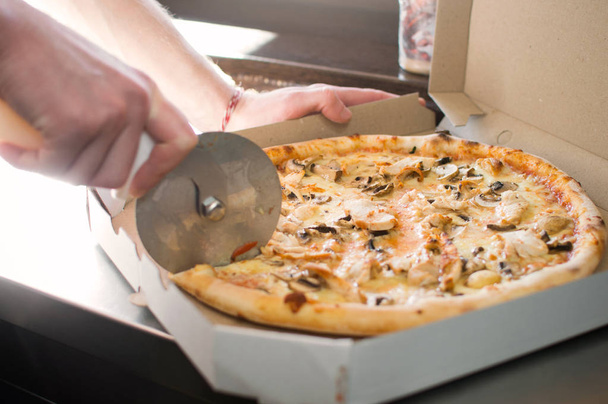 Cutting to cook pizza with olives in the box by the window. - Photo, Image