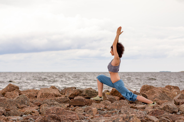 Young woman doing yoga exrecises outdoors - 写真・画像