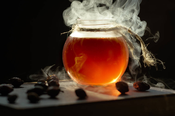 Una taza de té caliente al vapor negro puro, de cerca. Poción curativa ahumada mágica en botella
. - Foto, Imagen