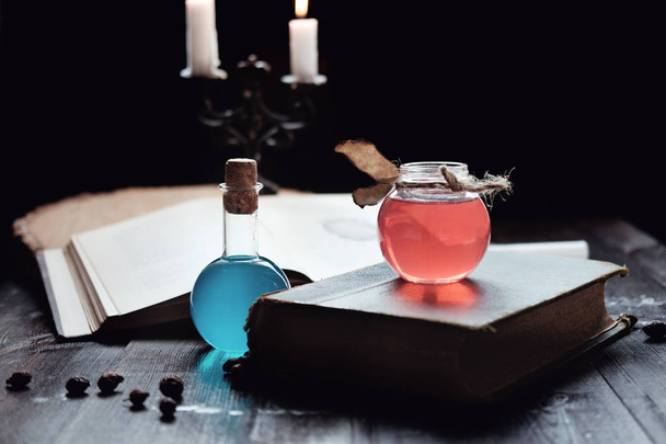Magie en tovenarij concept. Set van boek van tovenarij, magische drankjes en kaarsjes op tafel. Gezondheid en mana potion. Alchemie concept. - Foto, afbeelding