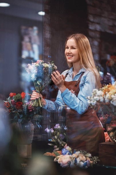 Hymyilevä kukkakauppias kukkakimppu myymälässä
 - Valokuva, kuva