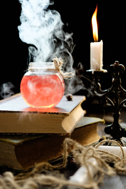 Magic and wizardry concept. Set of sorcery book, magic potions and candles on table. Health potion. Alchemy concept. - Photo, Image