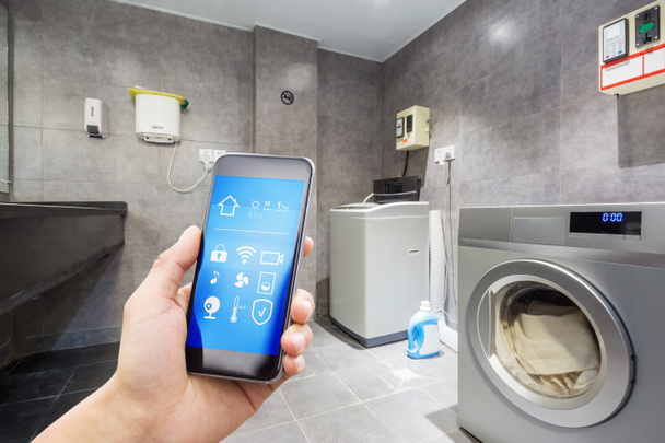 mobiele telefoon met smart home app in moderne Wasserij - Foto, afbeelding