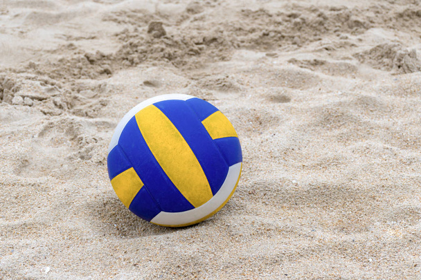 Voleibol azul y amarillo en la playa y huella en las arenas
 - Foto, imagen
