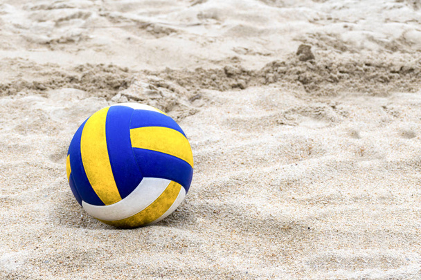 Voleibol azul y amarillo en la playa y huella en las arenas
 - Foto, Imagen