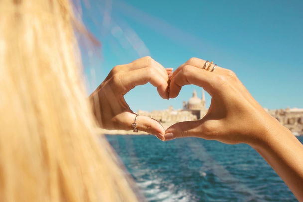 Młoda dziewczyna, co serce z rąk w pierścienie, symbol miłości z łodzi w piękny widok na Valletta, Malta - Zdjęcie, obraz