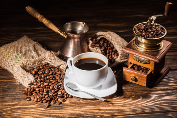 wysoki kąt widzenia filiżankę kawy z rocznika cezve i młynek do kawy na rustykalne drewniany stół rozlany z palonych ziaren - Zdjęcie, obraz