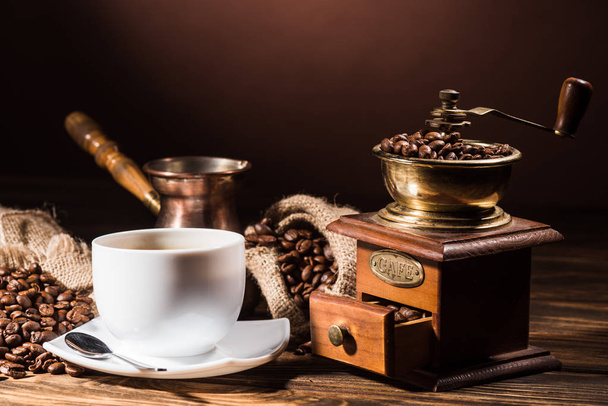 taza de café con cezve vintage y molinillo de café en mesa de madera rústica
 - Foto, Imagen