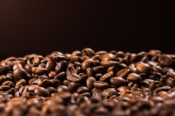 Nahaufnahme eines Haufens gerösteter Kaffeebohnen isoliert auf schwarz - Foto, Bild