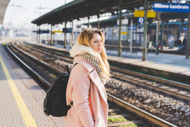 mujer joven al aire libre en la estación de tren esperando mirando hacia otro lado
  - Foto, imagen