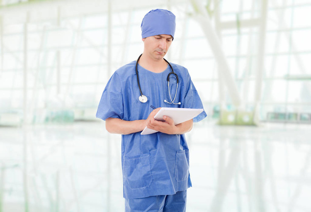 Άντρας γιατρός σκέφτεται με τις σημειώσεις του, στο νοσοκομείο - Φωτογραφία, εικόνα