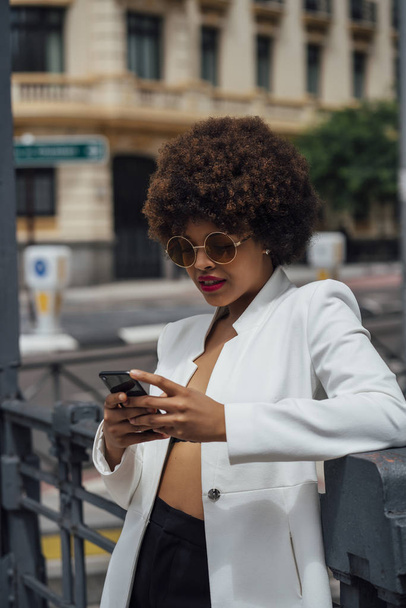 Mooie Afro hair meisje met mobiele telefoon in de straten van Madrid Spanje - Foto, afbeelding