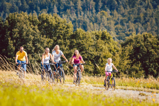 Семья катается на велосипеде днем в сельской местности
 - Фото, изображение