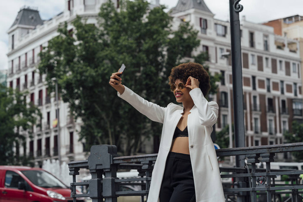 Beautiful Afro hair girl with mobile phone in the streets of Madrid Spain - Photo, Image