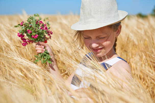 Kind steht im gelben Weizenfeld, strahlende Sonne, Sommerlandschaft - Foto, Bild