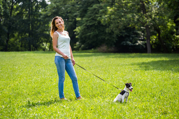 Beautiful woman enjoys walking with her  cute dog Jack Russell Terrier in the nature. - Фото, изображение
