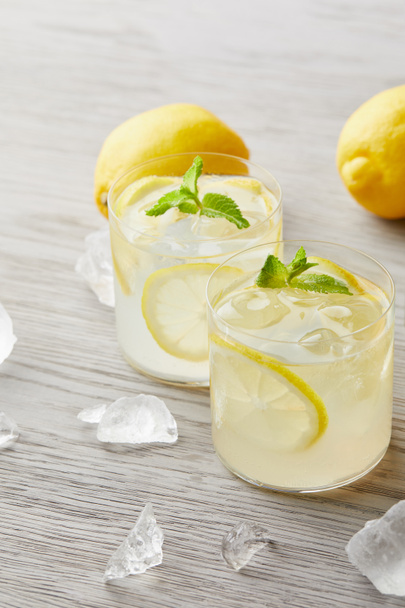 氷と木製の表面上のレモンでおいしいレモネードのガラス - 写真・画像