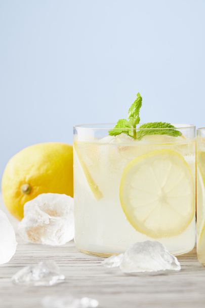 fresh glasses of lemonade with ice and lemon on wooden surface - Photo, image