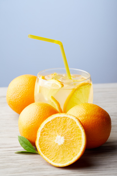 glas limonade met sinaasappelen op houten tafel - Foto, afbeelding