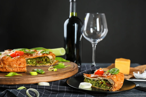 Tasty pie with spinach served for dinner on table against black background - Φωτογραφία, εικόνα