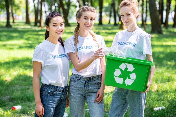 mulheres voluntárias bonitas com caixa de reciclagem em pé no parque
 - Foto, Imagem