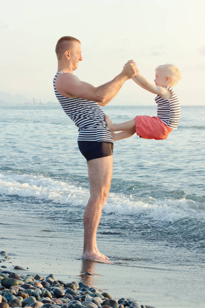 Apa és fia játszik a tengerparton. Szórakoztató időtöltés - Fotó, kép